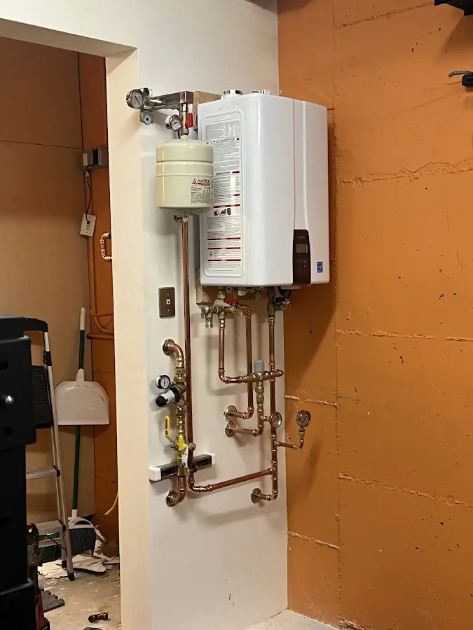 Plumbing technician inspecting water heater connections in Charles City